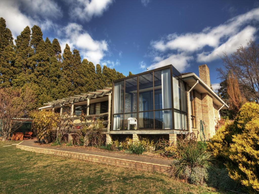 ein Haus mit Glasfenstern und Bäumen in der Unterkunft Derwent Vista in Austins Ferry