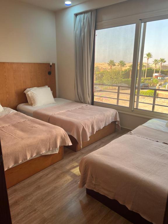 um quarto de hotel com duas camas e uma janela em The Home Dreamland em Cidade 6 de Outubro