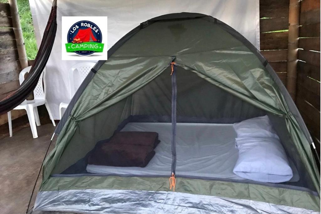 une tente verte avec un lit dans l'établissement CAMPING LOS ROBLES POPAYÁN, à Florencia