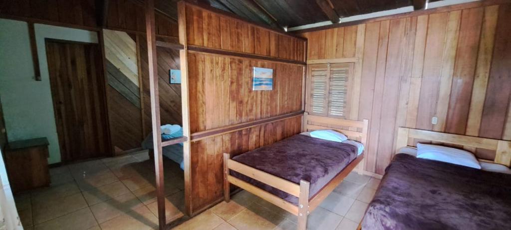 a room with two beds in a wooden cabin at Pochotel in Turrialba