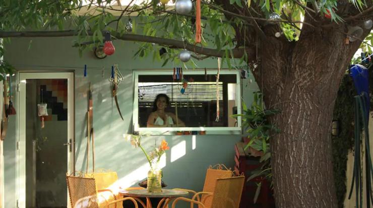 Kobieta patrzy w okno przyczepy. w obiekcie Habitaciones en casa encantada para viajeros w mieście Gualeguaychú