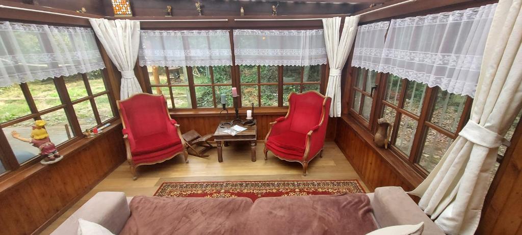 a living room with red chairs and a couch and windows at &#39;T boshuisje in Opglabbeek