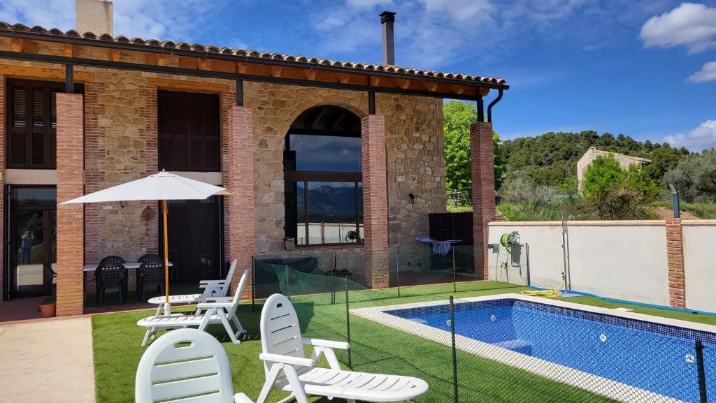 Casa con piscina con sillas y sombrilla en Mas De La Font en Lledó