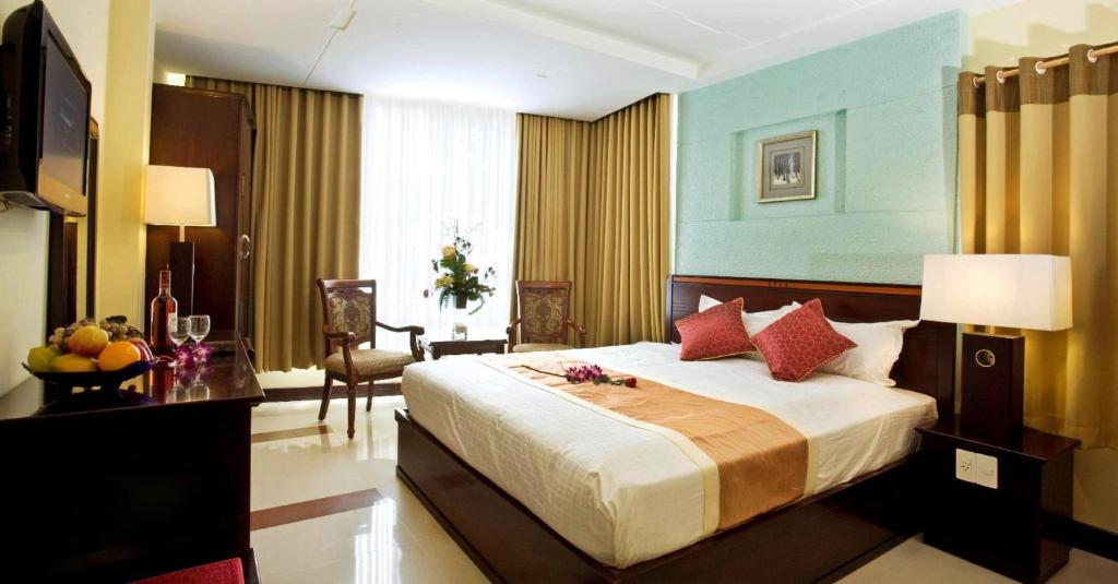 a bedroom with a large bed and a table with a bowl of fruit at Lien An Sai Gon Hotel in Ho Chi Minh City