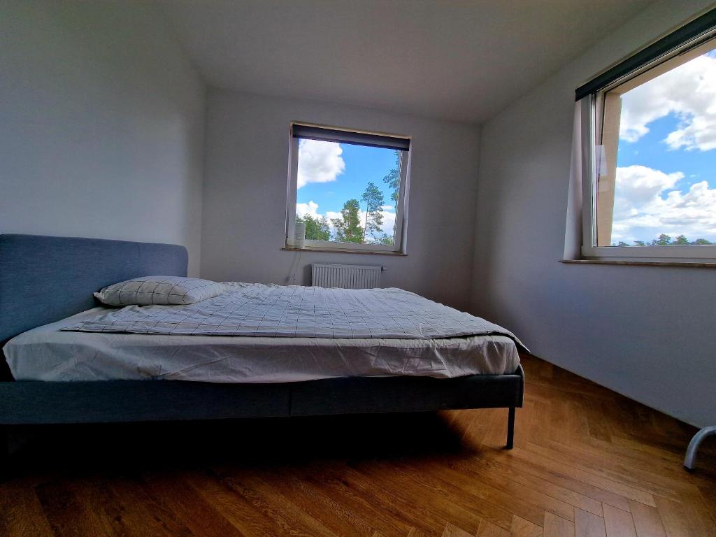 a bedroom with a bed and two windows at Piękny apartament położony w środku lasu in Dywity