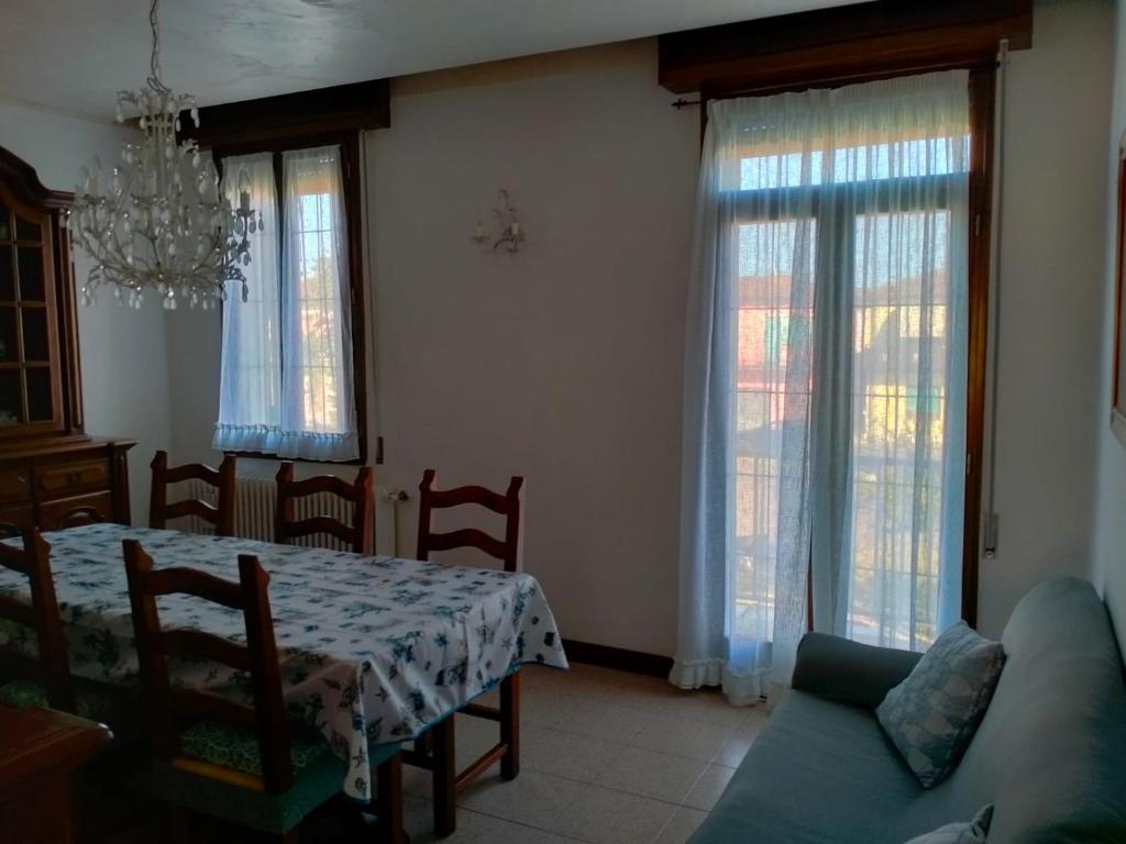 a living room with a table and a couch and windows at Casa nel Delta del Po in Scardovari