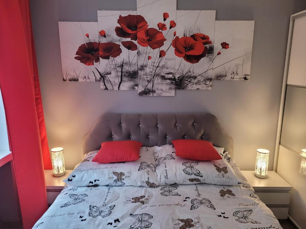 um quarto com uma cama com almofadas vermelhas e pinturas em Apertament JOWISZ em Zabrze