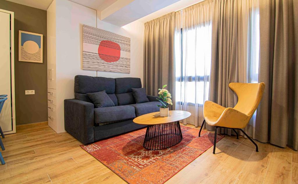 sala de estar con sofá azul y mesa en Apartamentos Leonor, en Málaga