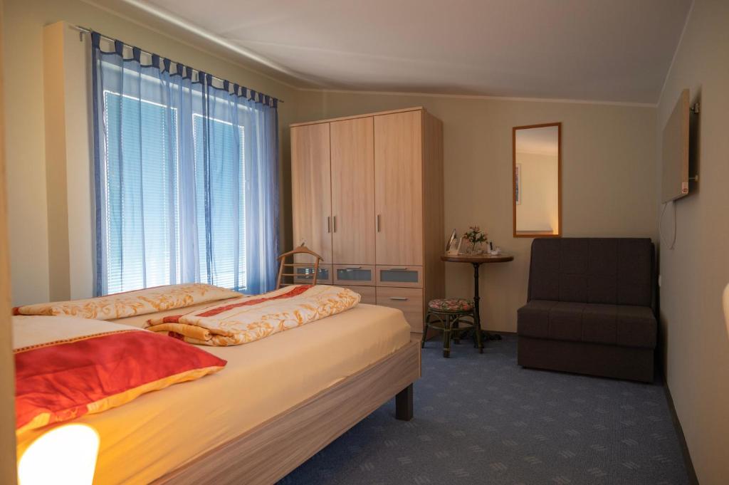 Mursko Središće的住宿－Apartmani Mura，一间卧室设有两张床、一把椅子和一个窗户。