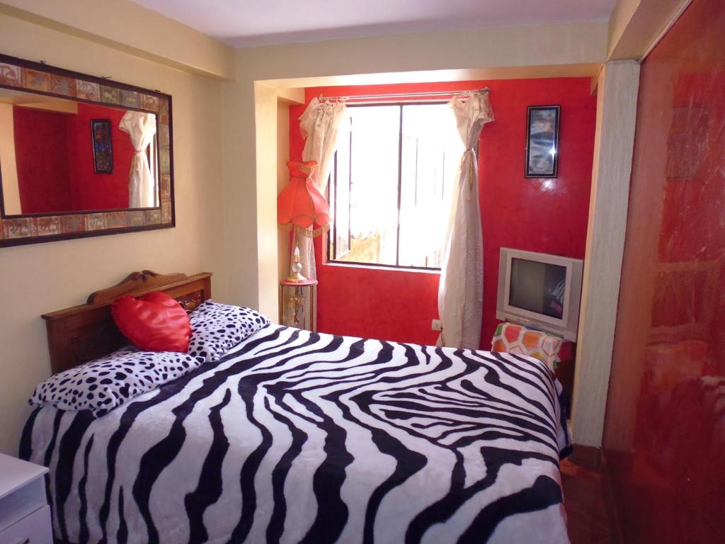 1 cama con estampado de cebra en un dormitorio con una pared roja en Hospedaje Pumacurco Betty, en Cusco
