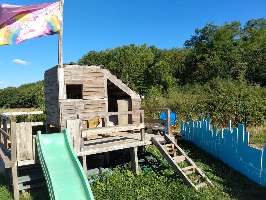 a wooden play house with a slide and a flag at Cabane Terrasse et potager in Rambouillet