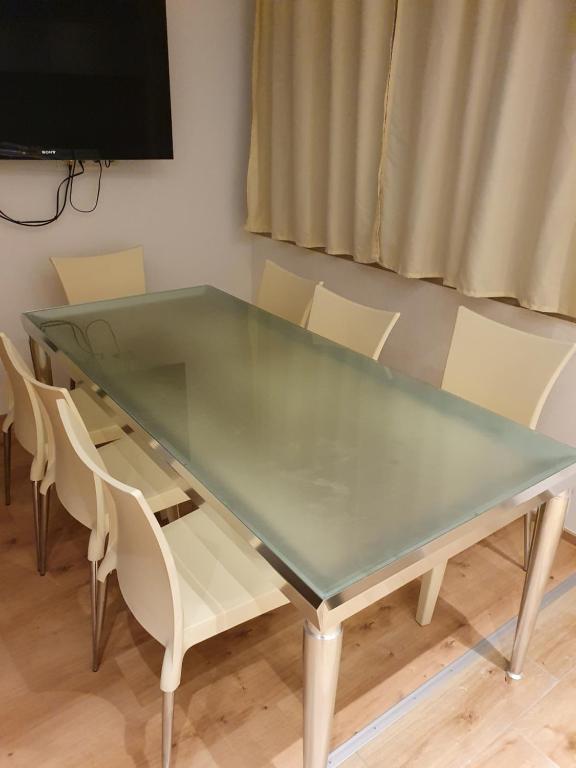 a glass table with white chairs and a television at Town House Rosenheim in Rosenheim