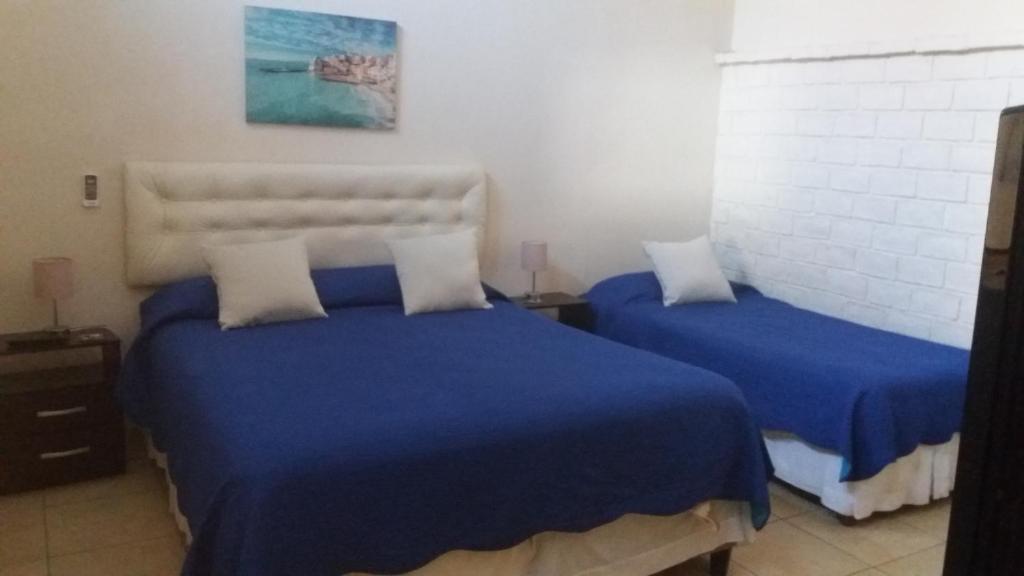 1 dormitorio con 2 camas y sábanas azules en Apartamentos del Este, en Piriápolis