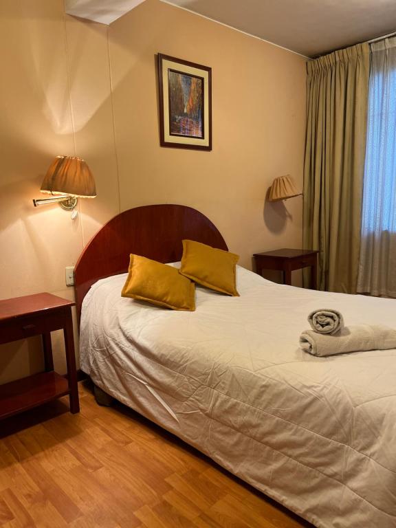 a bedroom with a bed with two yellow pillows at Hotel Vilandre in Cusco