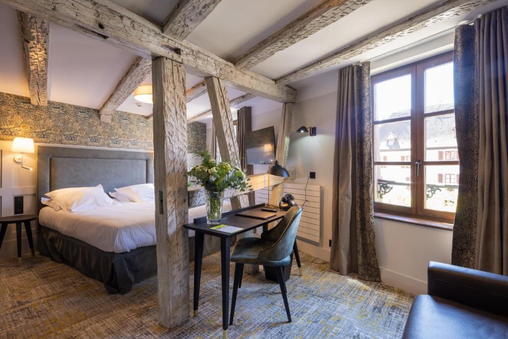 a hotel room with a bed and a desk at Hôtel-Restaurant du Mouton in Ribeauvillé