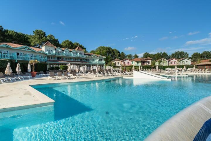 une grande piscine avec des chaises et des parasols dans l'établissement Appartement sur golf avec piscine chauffée à Lacanau-Océan, à Lacanau