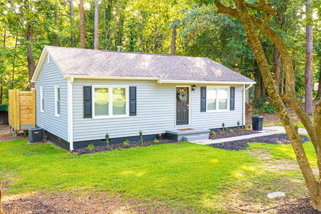 a small white house in the middle of a yard at Homey Bungalow Convenient to Marietta and I-75! in Marietta
