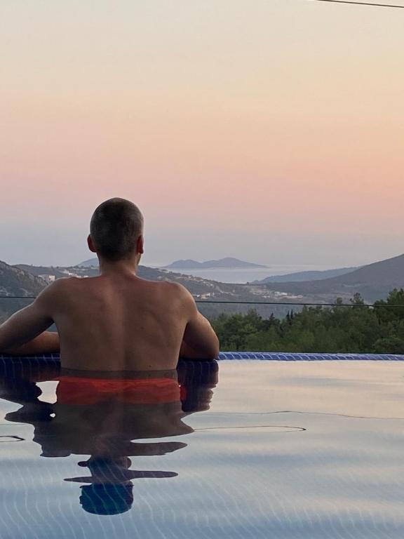 a man sitting in a infinity pool watching the sunset at LA VILLA CELINE- Luxury Sea View Villa with Private Infinity Pool in Islamlar-Kalkan in Kalkan