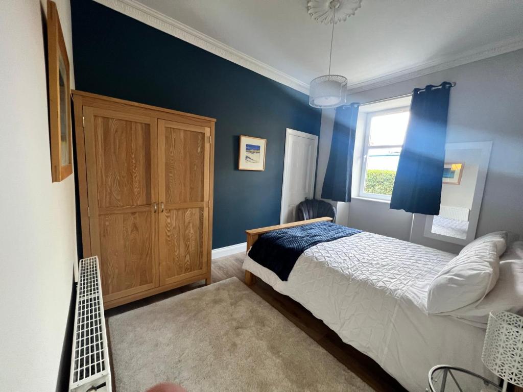 um quarto com paredes azuis, uma cama e uma janela em Central Helensburgh 1 BR, gr floor pet friendly em Helensburgh