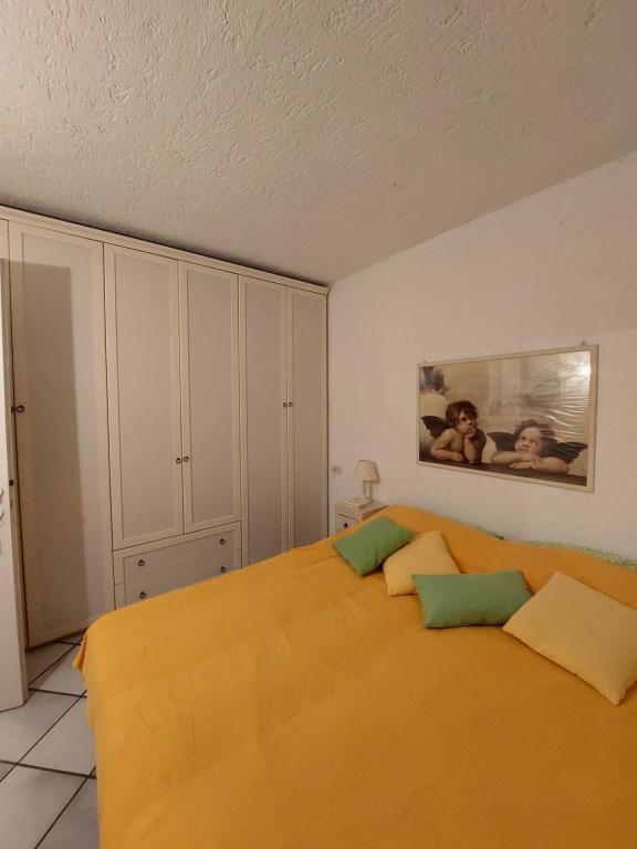 una camera da letto con letto, lenzuola arancioni e cuscini verdi di Appartamento a Punta Asfodeli a Porto Rotondo