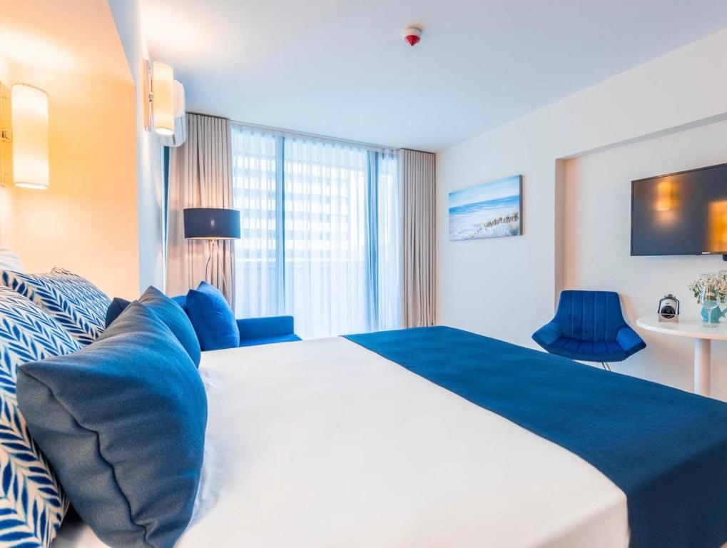 a bedroom with a large white bed with blue pillows at Orbi City Sea View Apartments in Batumi