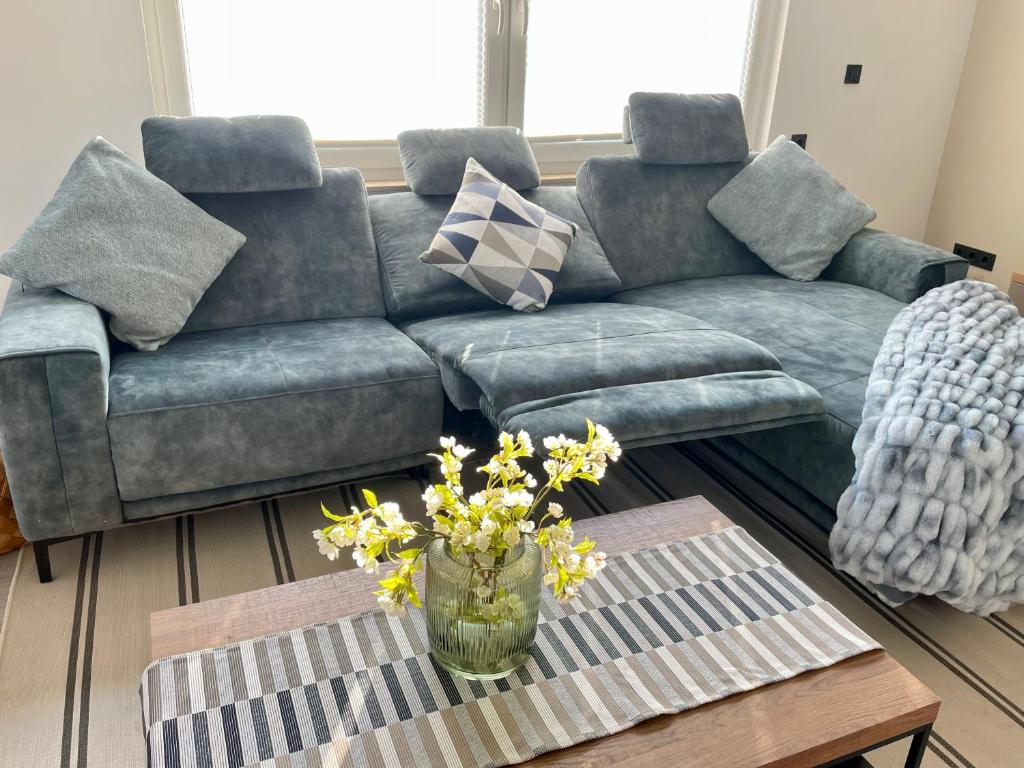 a living room with a couch and a table with flowers at Neu! Wellnesshome Fontaneweg Sauna, Terasse, Garten Erstbezug Juli 2022 in Espelkamp