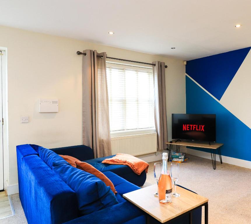 ラムズボトムにあるA superb large 1 bedroom apartment in Ramsbottomのリビングルーム(青いソファ、テレビ付)