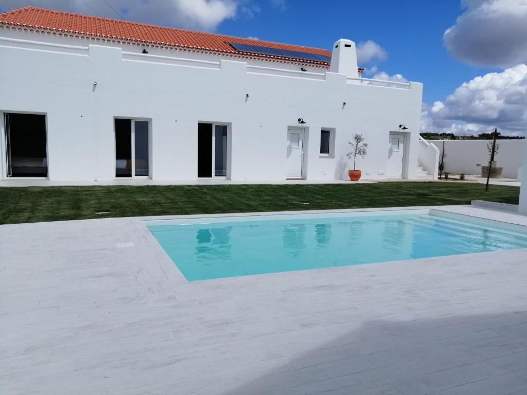 a swimming pool in front of a white house at Pé no Campo Suites and Villa in Carvalhal