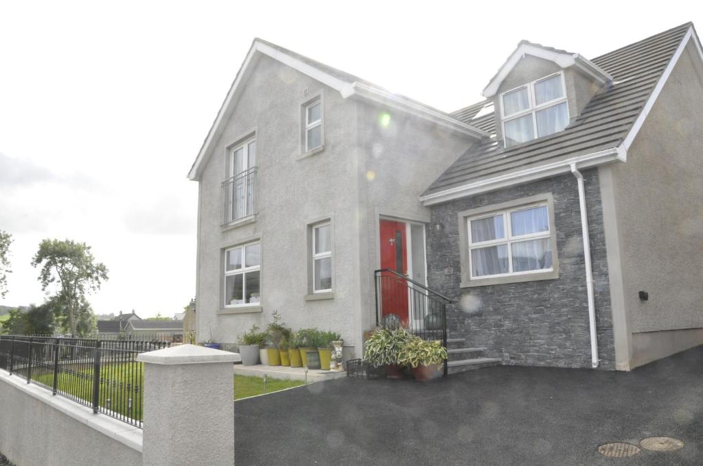 a gray house with a red door and a driveway at Hillside Luxury Bed & Breakfast in Ballycastle