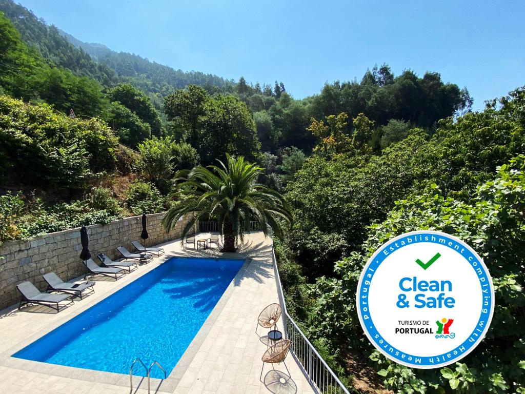 einen Pool mit Stühlen und ein Schild, auf dem sauber und sicher steht in der Unterkunft Chalet Villas Gerês in Geres