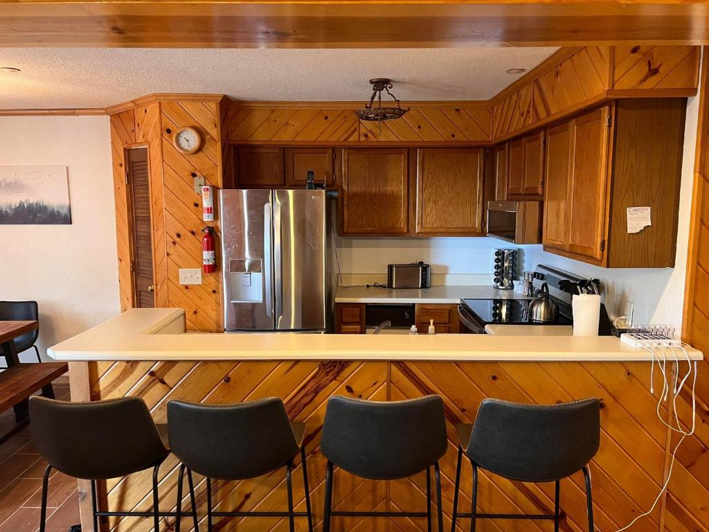 uma cozinha com armários de madeira e um balcão com cadeiras em Summit 204D at Snowshoe em Snowshoe