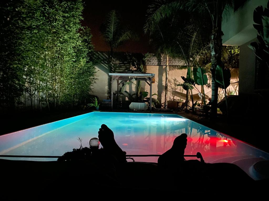 dos personas sentadas frente a una piscina por la noche en Villa Aïcha, en Marrakech