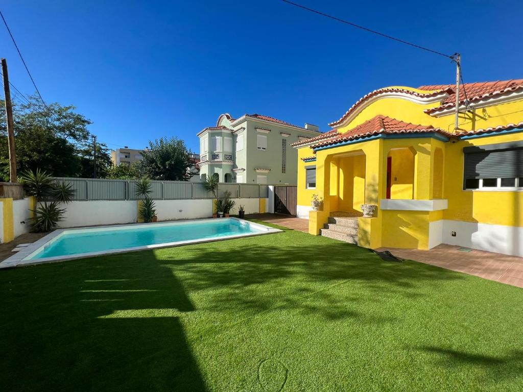 a yellow house with a swimming pool in a yard at Kali Vice Surf Villa in Costa da Caparica