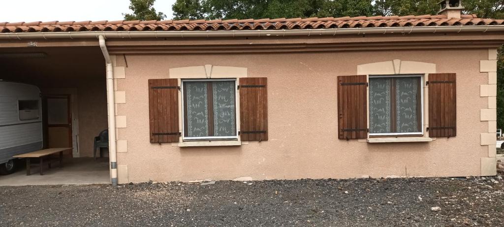 uma casa cor-de-rosa com duas janelas e um banco em Le paysage - Le studio PMR em Arsac-en-Velay