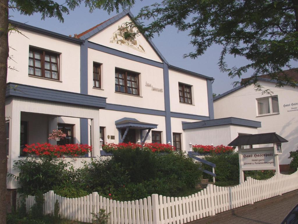 バート・ザクサにあるFerienwohnungen Hasenpattの赤い花と柵の白い家