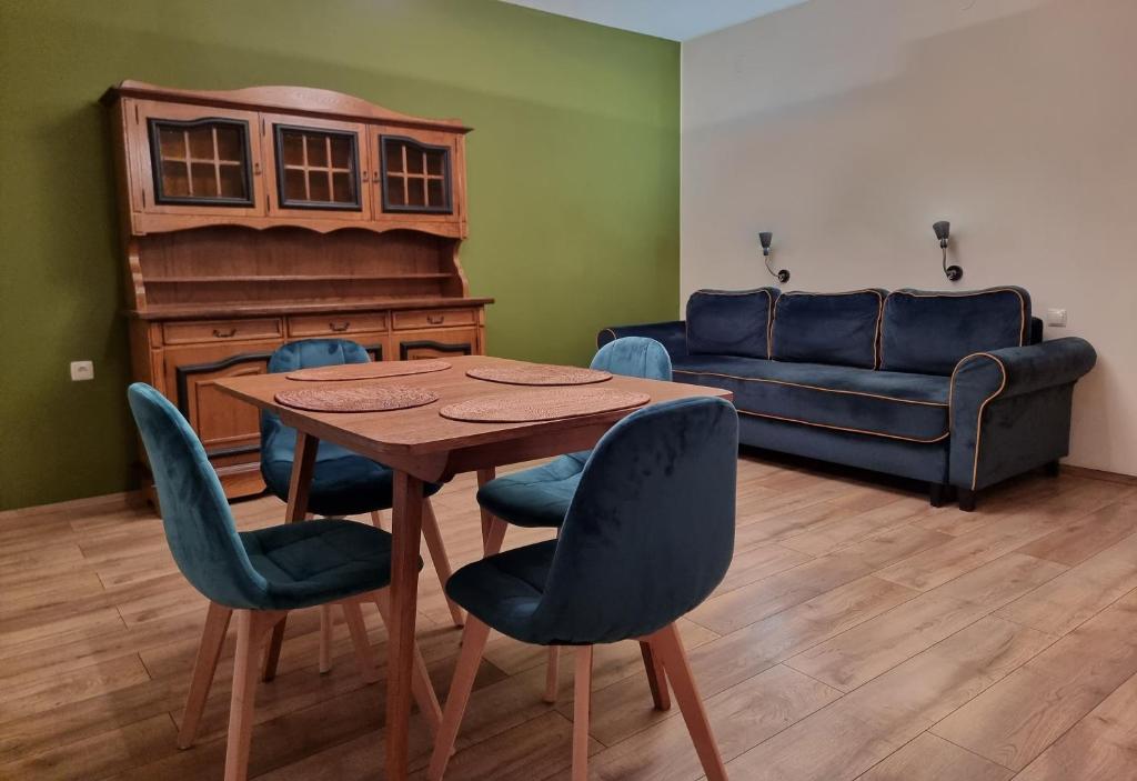 a living room with a wooden table and blue chairs at Komfortowy Apartament blisko plaży in Gdańsk