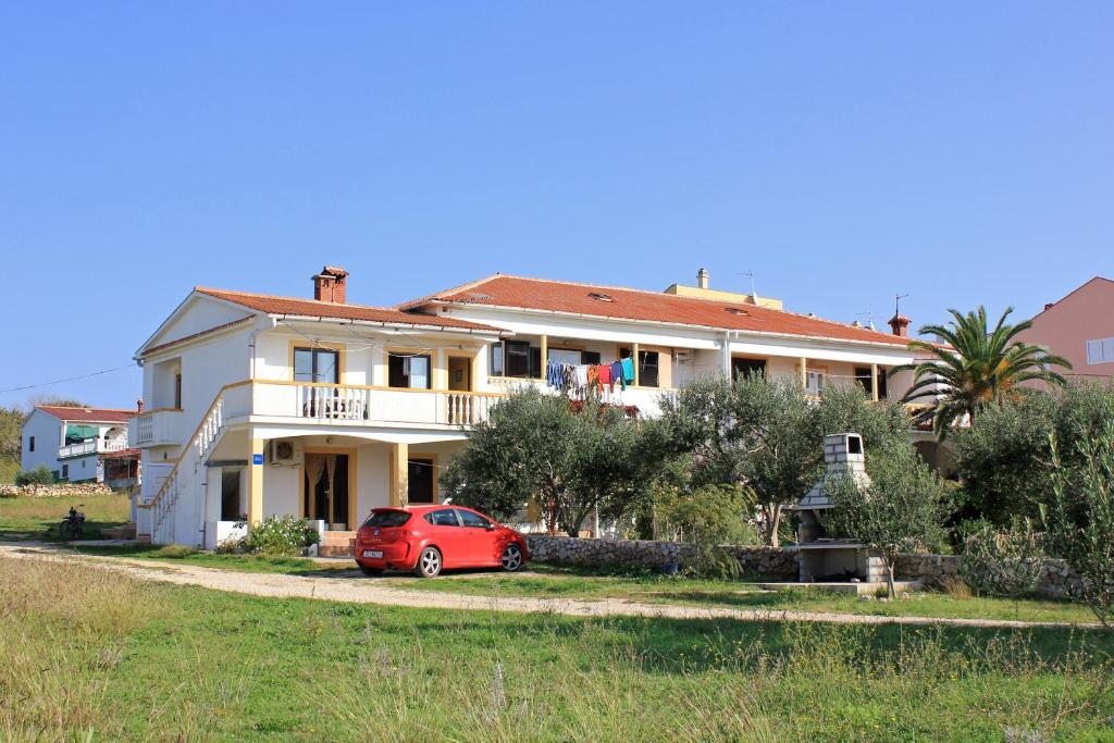 a red car parked in front of a house at Apartments with a parking space Povljana, Pag - 9405 in Povljana