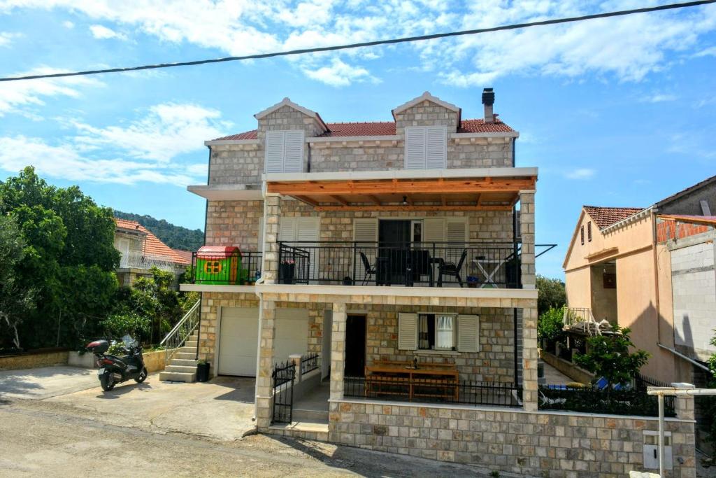 a brick house with a balcony on a street at Apartments by the sea Brna, Korcula - 10065 in Brna