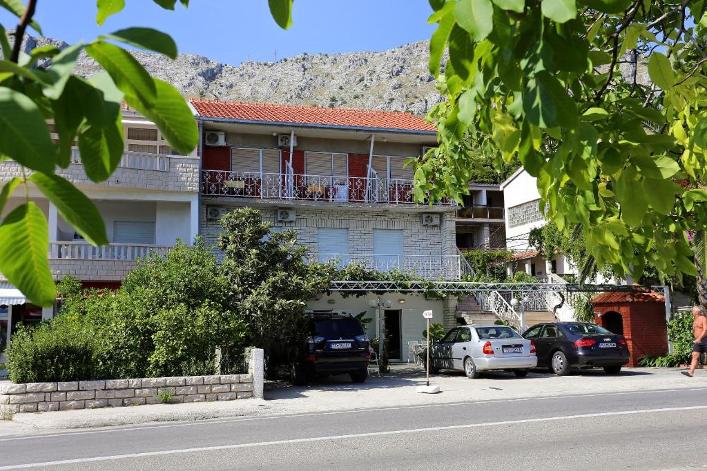 a building with a balcony and cars parked on the street at Apartments by the sea Duce, Omis - 10304 in Duće