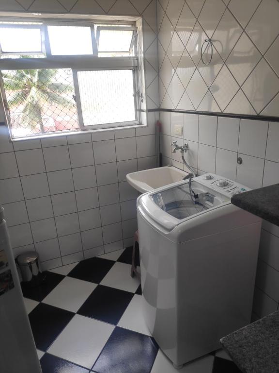 uma casa de banho com uma máquina de lavar roupa e um lavatório em Enseada- 400m Aquário. Apt espaçoso e aconchegante no Guarujá