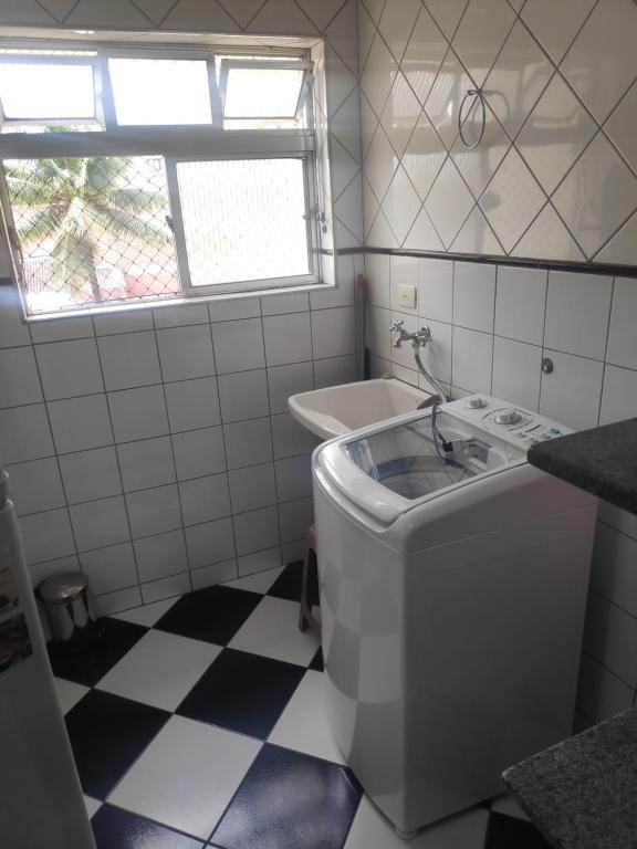 un bagno con lavatrice e lavandino di Enseada- 400m Aquário. Apt espaçoso e aconchegante a Guarujá