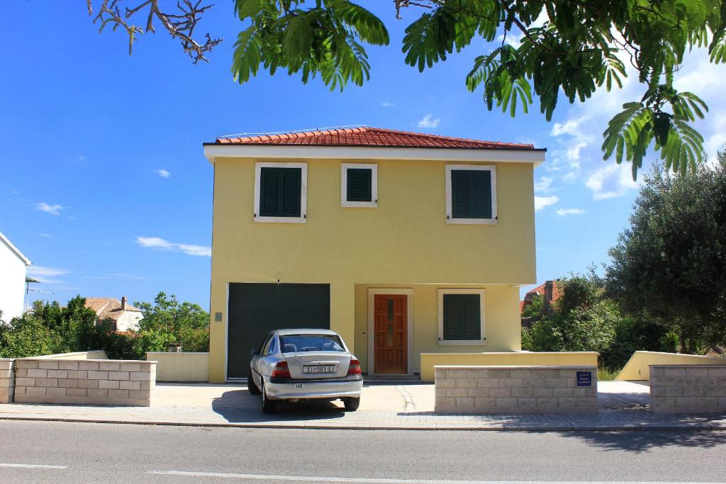 ein Auto, das vor einem gelben Haus parkt in der Unterkunft Apartment Orebic 10097a in Orebić