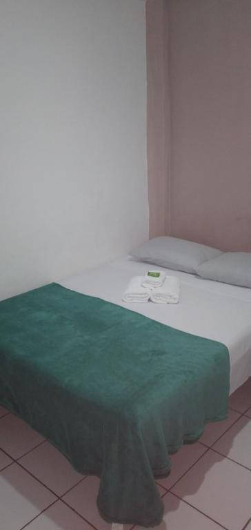 Una cama con una manta verde encima. en Pousada Brisa de Saquarema en Saquarema