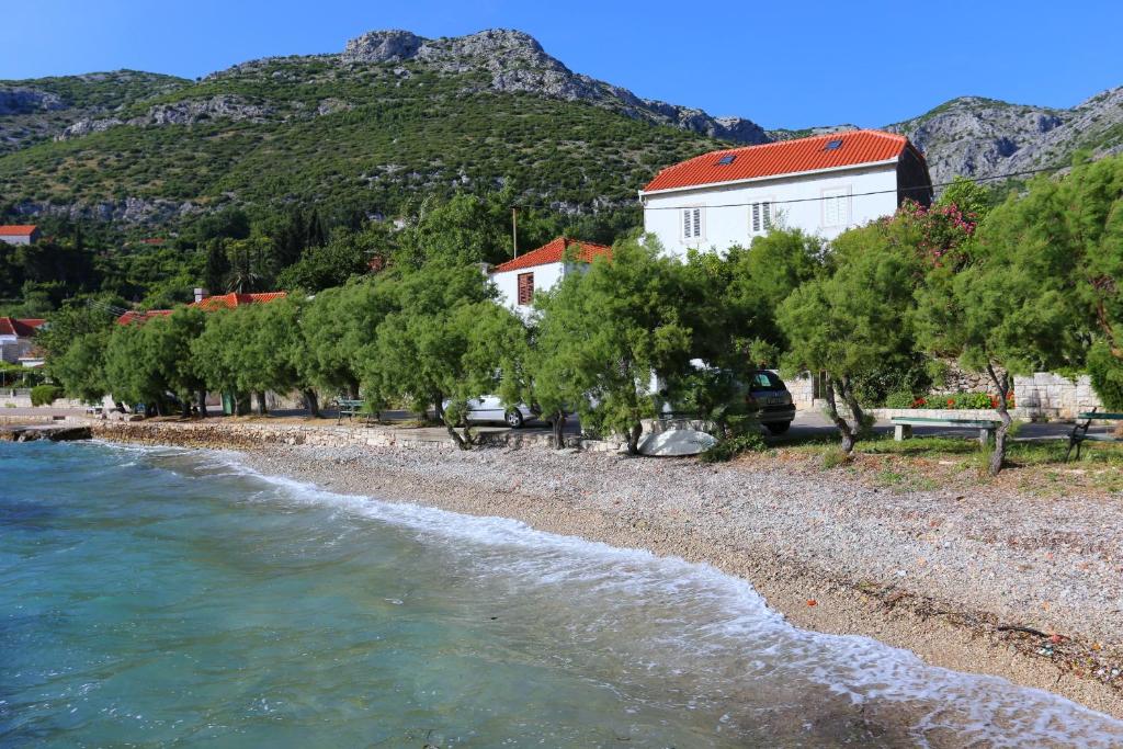 una playa con árboles, un edificio y una montaña en Apartments by the sea Viganj, Peljesac - 10140, en Viganj