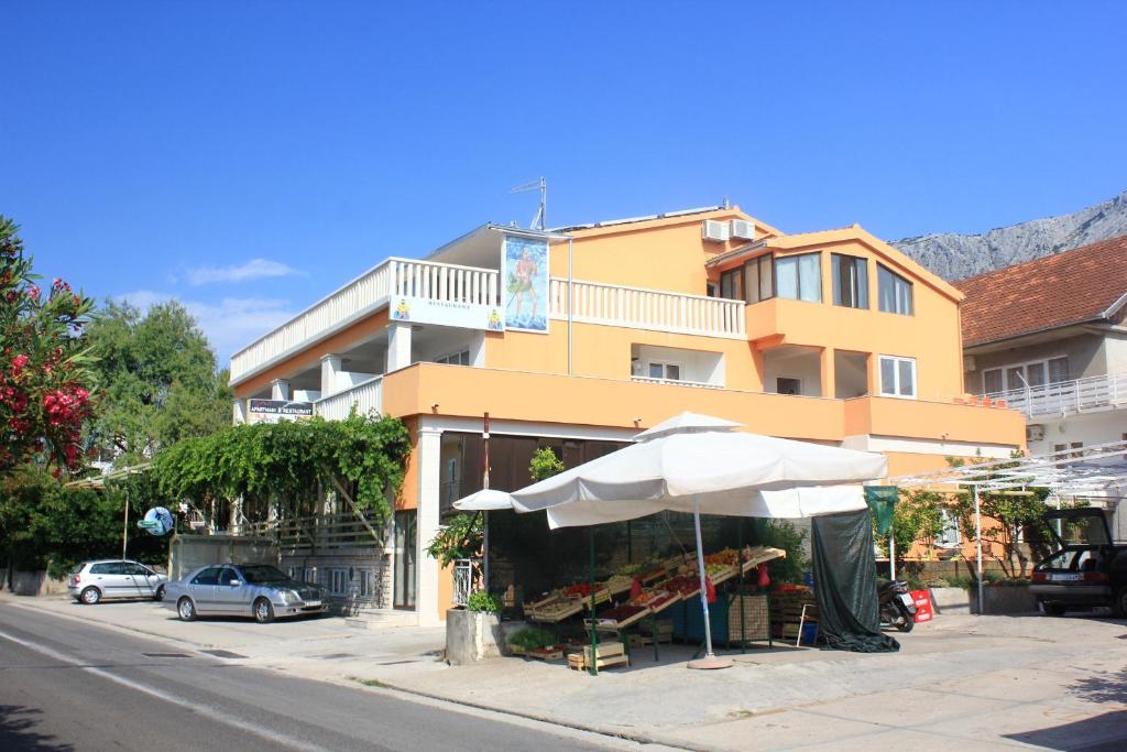 a fruit stand with an umbrella and a building at Apartments with parking space Orebic, Peljesac - 10088 in Orebić