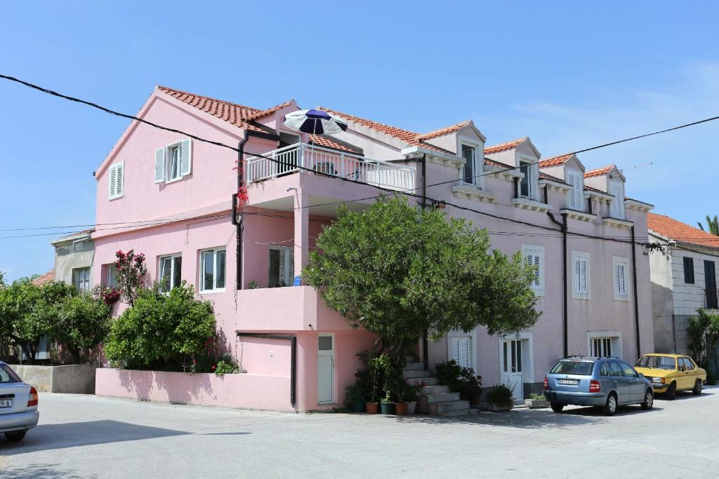 um edifício rosa com carros estacionados em frente em Apartments by the sea Sreser, Peljesac - 10105 em Janjina