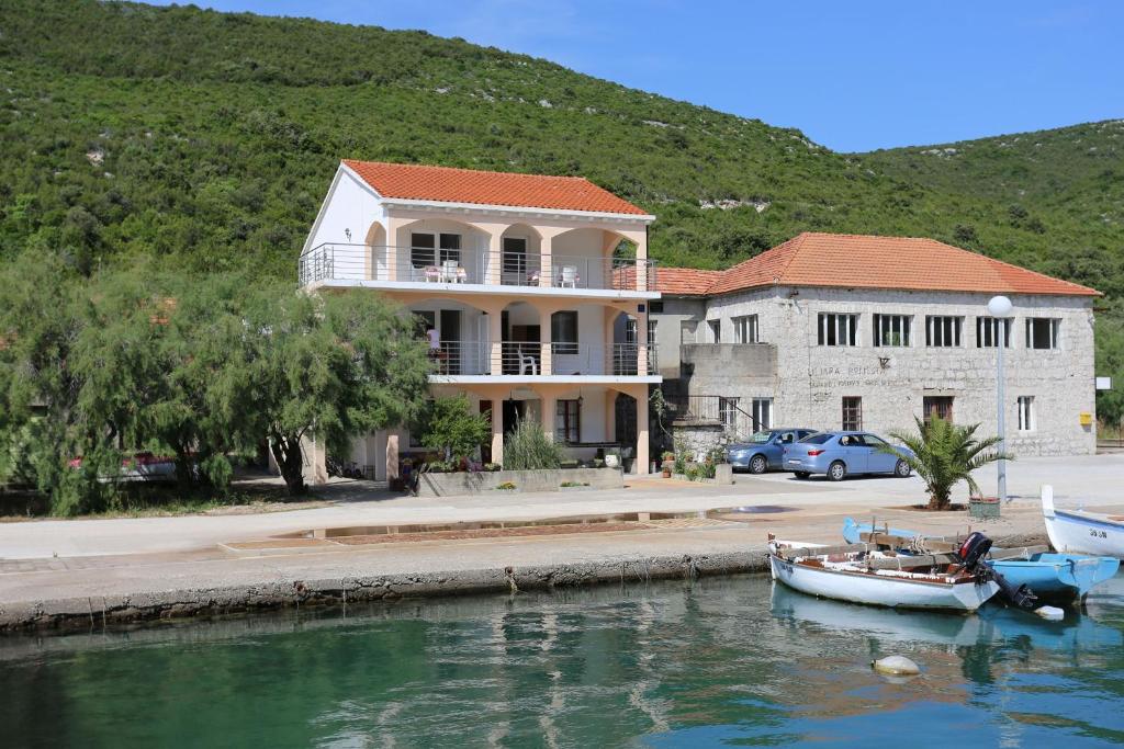a large house with a boat in the water at Apartments by the sea Brijesta, Peljesac - 10223 in Brijesta