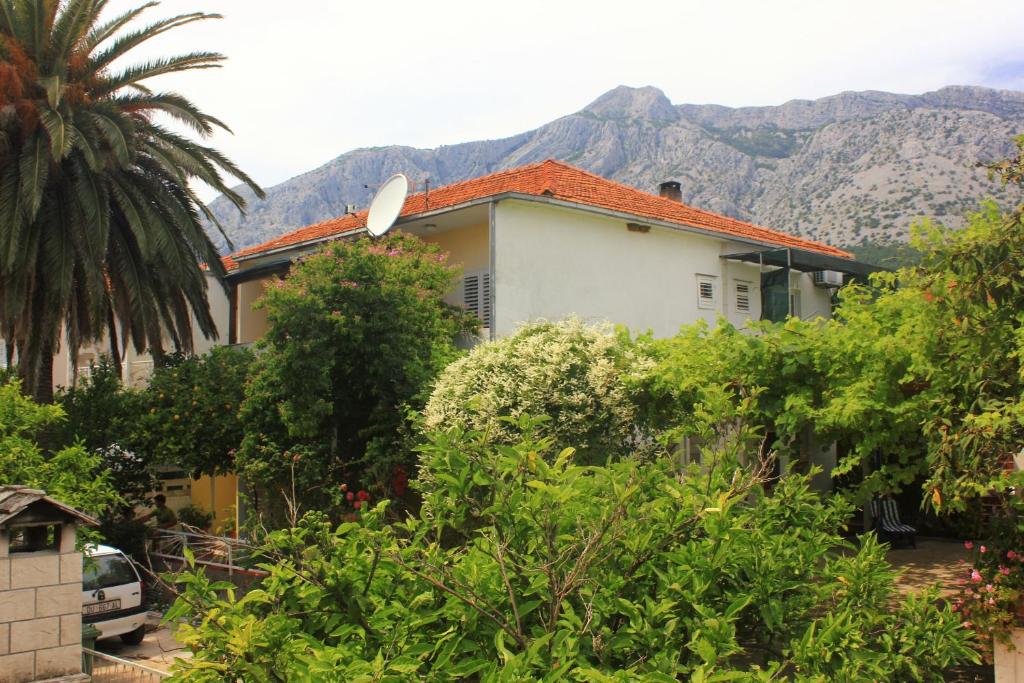 a house with a palm tree and mountains in the background at Apartments with a parking space Orebic, Peljesac - 10177 in Orebić