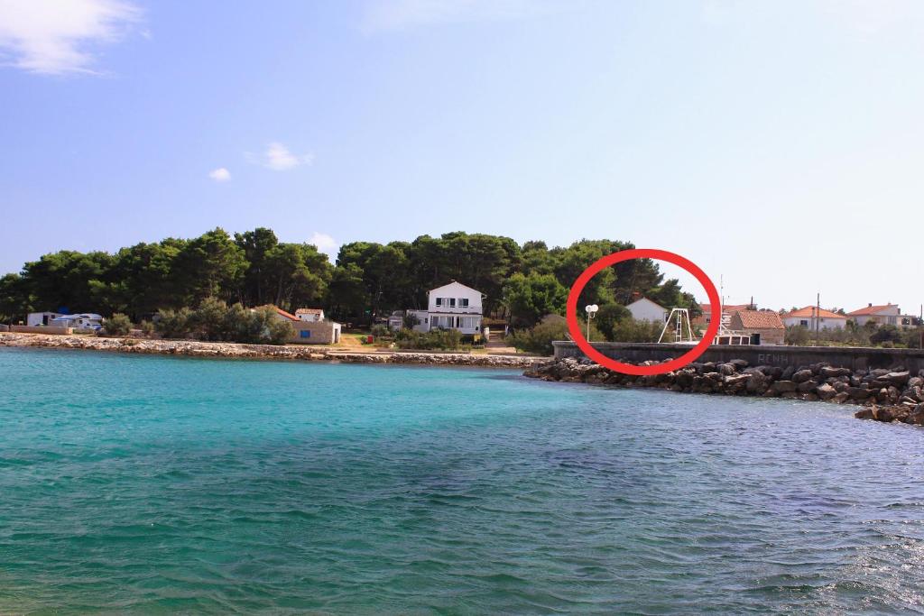 a red circle is sitting on the shore of a body of water at Seaside holiday house Susica, Ugljan - 9664 in Ugljan