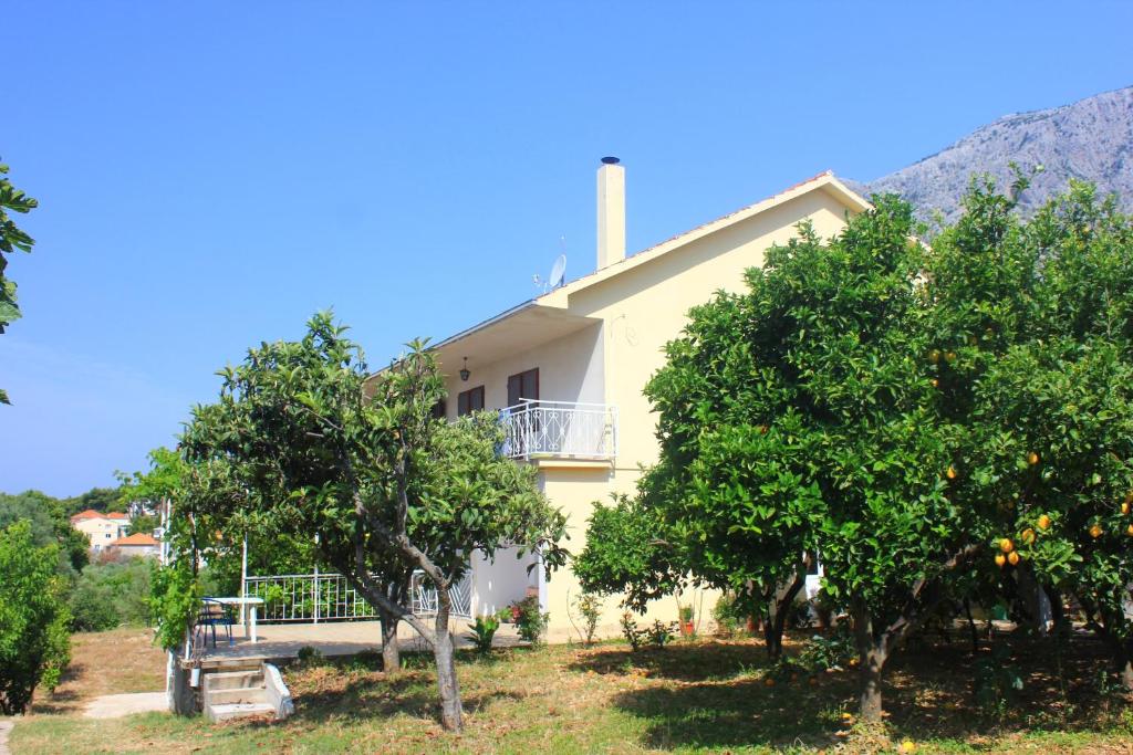 una casa amarilla con árboles delante de ella en Apartment Orebic 10256b en Orebić